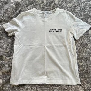 Vit t-shirt från Calvin Klein Jeans - säljer en vit t-shirt från Calvin Klein med tryck både fram och bak som passar både tjejer och killar. köpte ny för 500kr. använd och tvättad några gånger. skriv gärna vid frågor🩷pris är diskuterbart
