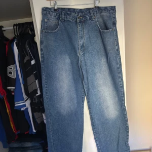 Blå jeansbyxor från Joker brand - Säljer ett par klassiska blå jeansbyxor från Joker. De har en straight passform med fem fickor och en knappgylf. Perfekta för en avslappnad stil. Märket 'Joker' är broderat på bakfickan.
