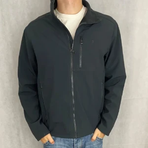 Svart jacka från Polo Ralph Lauren - Säljer en stilren svart jacka från Polo Ralph Lauren, i storlek L men sitter mer som M. Jackan har en dragkedja framtill och flera praktiska fickor med dragkedjor. Perfekt för en casual look. Kan gå ner i pris vid snabb affär.