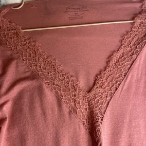 Rosa långärmad topp från Intimissimi - Säljer en elegant rosa långärmad topp från Intimissimi med v-ringning och spetsdetaljer vid hals och ärmslut. Perfekt för en stilren look. 💖