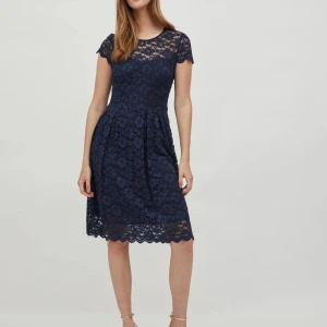 Mörkblå spetsklänning - Elegant mörkblå klänning i spets med korta ärmar och rund hals. Klänningen har en vacker blommig spetsdesign och en feminin passform som slutar strax ovanför knäna. Perfekt för speciella tillfällen. Har bara använt den en gång på ett bröllop. Har ingen användning av den längre och det är därför jag säljer.