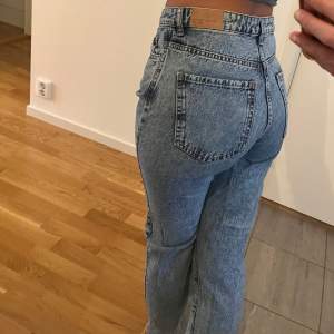 Snygga blå jeans från Gina Tricot med hög midja och klassisk femficksdesign. De har en straight passform och är perfekta för en avslappnad stil. Jeansen har en knapp och dragkedja framtill.
