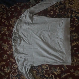 Ljusblå tröja från Tommy Hilfiger - Säljer en stilren ljusblå tröja från Tommy Hilfiger. Tröjan har långa ärmar och en liten logotyp på bröstet. Perfekt för en avslappnad och snygg look.