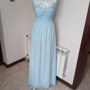 Ljus blå balklänning/festklänning - Ljusblå balklänning från sistaglam i storlek 8. Passar mig som har storlek s/xs. Jättefina detaljer och känns lyxig. Jag hade tidigare planer på att sy bort den genomskinliga överdelen så att den blir armlös, men gör vad du vill såklart. Lite sliten vid dragkedjan, men ser värre ut än vad det är. Dragkedjan funkar fortfarande praktiskt, skavanken syns ej när man har dragkedjan stängd.  Skriv gärna vid frågor💕