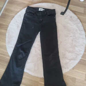 Svarta bootcut jeans från 157 - Snygga svarta bootcut jeans från 157 med klassisk femficksdesign. De har en knapp och dragkedja framtill samt dekorativa knappar på bakfickorna. Perfekta för en stilren look.