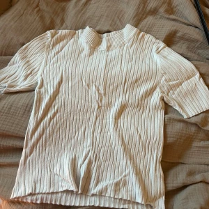 Vit ribbad tröja från Gina Tricot - Säljer en stilren vit ribbad tröja från Gina Tricot. Tröjan har korta ärmar och en bekväm passform. Perfekt för en enkel och snygg look. Är i storlek M, något längre ärm en normallängd. Sparsamt använd!