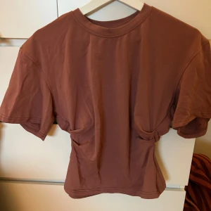 Figursydd T-shirt  - Sjukt snygg T-shirt i riktigt bra material och snygga detaljer i ryggen. Lite längre ärm och sjukt snygg på kroppen, gammelrosa färg. Är i storlek L men liten i storlek så passar XS/S. Använd 1 gång!