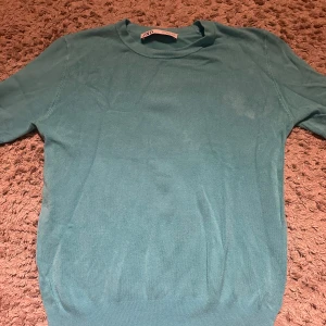 Stickad T-shirt - Säljer en snygg turkos tröja från Zapa. Tröjan har korta ärmar och en rund halsringning, perfekt för en stilren look. Den är tillverkad i ett mjukt material som känns skönt mot huden. Passar bra till både jeans och kjol. 🌟