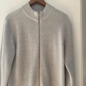 Grå stickad kofta med dragkedja - Säljer en stilren grå stickad kofta med dragkedja. Perfekt för kyligare dagar med sin mjuka och bekväma passform. Koftan har långa ärmar och en hög krage som ger extra värme. Ett mångsidigt plagg som passar till det mesta. Använd 2 tillfällen. Tveka inte på att höra av dig vid frågor eller funderingar! Mvh Sixten 