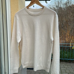 Vit merinoulltröja från These Glory Days - Säljer en stilren vit tröja från These Glory Days i mjuk merinoull. Tröjan har en klassisk design med rund hals och långa ärmar, perfekt för både vardag och mer uppklädda tillfällen. Helt ny utan prislapp 