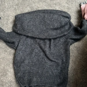 Mörkgrå stickad tröja från H&M - Säljer en mysig mörkgrå/blå stickad tröja från H&M. Tröjan är off shoulder och långa ärmar, perfekt för kyliga dagar. Den är ribbad vid ärmslut och nederkant för extra komfort. Passar perfekt till höst- och vintergarderoben.