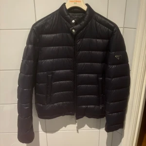 Prada pufferjacka - Säljer min Prada Dunjacka. Storlek 52 vilket motsvarar XL. Passar folk som bär L-XL. Marinblå färg.  Använd 3-4 gånger och är som i nyskick. Nypris 10000kr