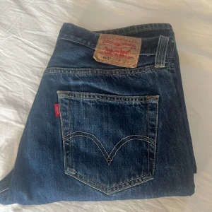 Levi's 501 jeans - Klassiska Levi's 501 jeans i en snygg blå tvätt. Dessa jeans har en rak passform och är tillverkade i slitstarkt denim. Perfekta för en avslappnad stil med den ikoniska röda Levi's etiketten på bakfickan.