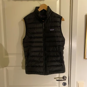 Dunväst Patagonia - Säljer en svart dunväst från Patagonia storlek S i mycket bra skick. Den är lätt och smidig att bära, med en klassisk design som passar till det mesta. Perfekt för lager-på-lager-stil. Inga defekter. Passar dig upp till 180cm.