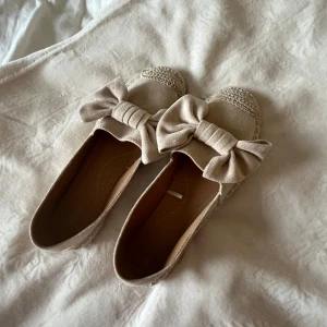 Beige ballerinaskor med rosett - Säljer ett par söta beige ballerinaskor med stora rosetter framtill. Dem är endas använda 2-3 gånger och därav priset!
