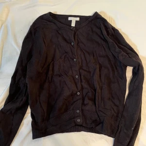 Svart cardigan med knappar - Säljer denna svarta cardigan från HM. Tunt och skönt material. Storlek L men passar som en S.