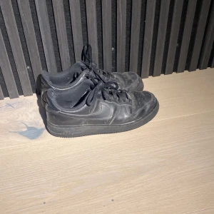 Svarta Nike Air Force sneakers - Svarta Nike Air Force sneakers som hsr några skador(se bilderna) men som fortfarande är snygga. Använder aldrig dessa så säljer dom billigt
