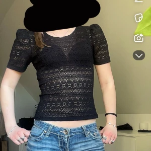 Svart spetsblus - Säljer en elegant svart spetsblus med korta ärmar och ett vackert mönster. Perfekt för att ge en stilren look. Blusen har en tight passform och är tillverkad i ett mjukt material.