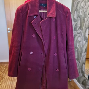 Vinröd kappa - Snygg vinröd kappa med dubbelknäppning och klassisk krage. Perfekt för kyliga dagar med sin stilrena design och långa ärmar. Ett måste för garderoben!