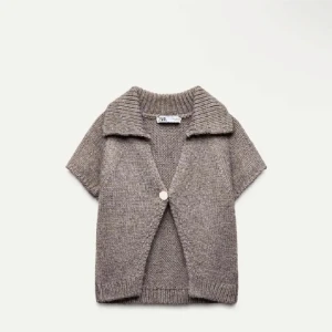 Beige stickad kofta från Zara - Säljer en snygg beige stickad kofta från Zara med korta ärmar och en stor knapp framtill. Perfekt för lager. Endast använd en gång och är i mycket bra skick💕