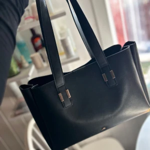 Svart väska - Elegant svart axelväska med stilrena linjer och långa handtag. Köpt från Zalando. Märke - Anna Field.
