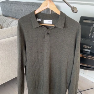 Olivgrön pikétröja från Selected Homme - Snygg olivgrön pikétröja från Selected Homme. Tröjan har en klassisk krage med knappar och långa ärmar. Perfekt för en stilren look.