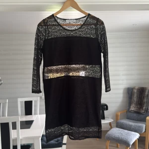 Klänning från  Rodebjer - Supersnygg svart spetsklänning från Rodebjer med långärmade ärmar och transparenta spetsdetaljer. Klänningen har ett elegant mönster i spetsen som ger en cool och sofistikerad vibe. Perfekt för dig som gillar stilrena och trendiga plagg.