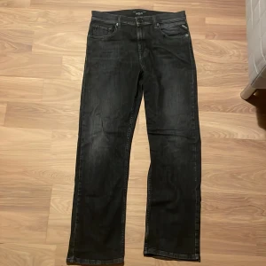 Svarta Replay jeans Thad - Säljer ett par svarta jeans från Replay med klassisk femficksdesign och raka ben. Jeansen har diskret tvättad look och Replay-logga på myntfickan. Materialet är jeans med snygg struktur och passformen är straight fit. Perfekta för en stilren vardagslook.