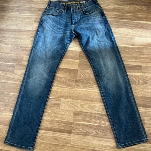 Lee Extreme Motion MVP jeans blå - Säljer ett par Lee Extreme Motion MVP jeans i klassisk blå tvätt med snygga slitningar. Modellen har slim fit med tapered ben, fem fickor och bekväm stretch. Perfekt för dig som vill ha både stil och rörelsefrihet. Jeansens midja är normal och passformen är slim.
