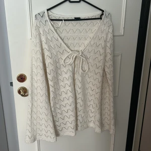 Vit stickad tröja med knyt från Gina Tricot - Supersöt vit stickad tröja från Gina Tricot i storlek M. Tröjan har ett snyggt zigzag-mönster, v-ringning med knyt framtill och långa ärmar. Perfekt för lager-på-lager och chill vibes. Materialet är mjukt och luftigt, passar både till jeans och kjol. Säljer eftersom den inte passar mig men den är helt oanvänd💕Nypris 359,59 kr