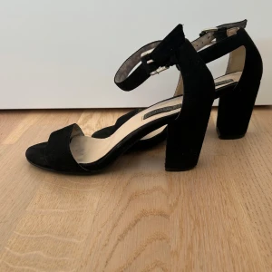 Svarta mockasandaler med klack - Svarta klackar från Nelly. En del fläckar som ej syns när man har på sig skon, därav priset. supersköna. Strl 36