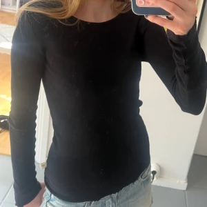 Svart ribbad långärmad tröja - Svart långärmad tröja med ribbad struktur och rund hals. Modellen är tight och sitter snyggt mot kroppen, perfekt att styla med jeans eller kjol. Enkel och stilren design som funkar till många olika looks. Skriv vid minsta fråga!💕💕