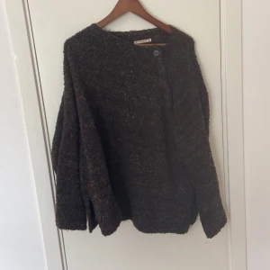 Mörkbrun kofta från Pull&Bear - Säljer en mörkbrun kofta från Pull&Bear i storlek M. Koftan har ett grovstickat material med små färgade inslag och knäppning framtill med två knappar. Perfekt för dig som gillar en chill och oversized look under höst och vinter.
