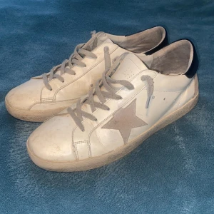  Golden Goose  - Snygga vita sneakers från Golden Goose med en grå stjärna på sidan och svart häl. Bra skick ändå. Typ 7/10