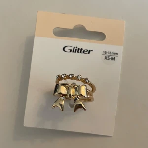 Guldiga ringar från Glitter - Tre ringar från Glitter, en med en rosett, en med små glittrande stenar och en vanlig plain. Stl xs-m, 16-18mm💛 Kolla gärna in mina andra annonser, ska flytta i slutet av augusti så försöker bli av med allt innan dess💝pris alltid förhandlingsbart, brukar gå med på de flesta prisförslag!😚
