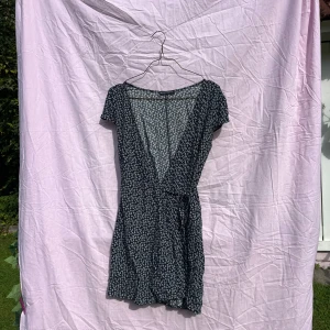 Blommig omlottklänning Brandy Melville - Supersöt kort omlottklänning från Brandy Melville i marinblått med små vita blommor. Klänningen har korta ärmar, knyt i midjan och v-ringning. Perfekt för sommarens alla tillfällen och riktigt skön i lätt viskosmaterial! Passar strl. 34-38 bäst