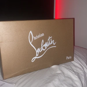 Mörkblå sneakers från Christian Louboutin - Snygga mörkblå sneakers från Christian Louboutin med klassisk röd sula och broderad logga på hälen. Skorna har rund tå, platt sula och är tillverkade i mocka med snörning framtill. Insidan är beige och ger en lyxig känsla. Perfekt för dig som gillar exklusiva detaljer.
