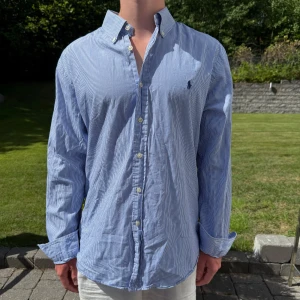 Blå randig Ralph Lauren skjorta - Blå/ vit randig Ralph lauren skjorta || Storlek L (Slim Fit) || Skjortan är i bra skick || Modellen på bilden är 170cm och väger 62kg || Tveka inte på att höra av dig vid frågor eller funderingar 
