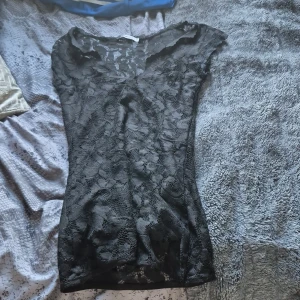 Svart spetsblus från Gina Tricot XS - Supersnygg svart blus från Gina Tricot i storlek XS. Blusen är helspets med blommigt mönster och har en v-ringad hals. Den är figurnära och har korta ärmar. Perfekt för dig som gillar att sticka ut med coola detaljer och transparent look och för alla med sthlm stil.