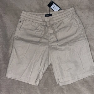 Matinique linne shorts - Snygga beige shorts från Matinique med elastisk midja och snörning framtill. Prislapp kvar från Åhlens för att jag köpte fel storlek men glömde kvitto. Modellen har två riktiga sidofickor och två låtsas bakfickor. Perfekta för varma dagar. Stilren look som passar till t-shirt eller skjorta. 