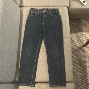 Mörkblå Lee jeans straight fit - Snygga mörkblå jeans från Lee med klassisk femficksdesign och raka ben. Jeansen har kontrastsömmar, Lee-logga på bakfickan och knapp med Lee-märke framtill. Materialet är slitstarkt denim i bomull och passformen är straight med normal midja. Passar mellan 150-160cm inga fel på jeansen om de är något är de bara att höra av sig!