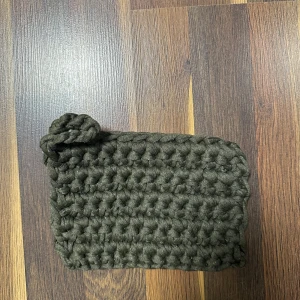 Mörkgrön chunky stickad grytlapp  - Handgjord chunky stickad grytlapp i mörkgrönt med en söt knutdetalj på sidan. Perfekt för dig som gillar unika accessoarer. 