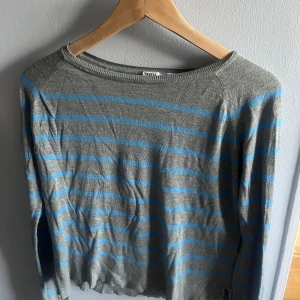 Gråblå randig tröja från Zara - Säljer en tunn, stickad tröja från Zara i storlek S. Tröjan är grå med ljusblå horisontella ränder och har en klassisk rund halsringning. Långärmad och med ribbade muddar vid ärmslut och nederkant. Köpte för typ 3 år sen när dessa va trendiga.