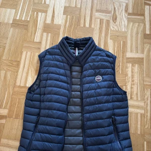 Mörkblå dunväst från Colmar Storlek M - Säljer min colmar väst som är i väldigt bra skick då jag har använt den i cirka 1 år nu. Storlek M  Hör av om ni har några frågor!