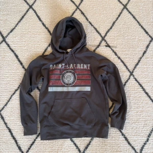 Saint Laurent hoodie - Säljer denna fina saint Laurent hoodie i storlek M men den passar nog bättre till S skulle jag säga är M och den passar inte mig följer med en liten hängare grej se bild ett, köpte på vinted så inte helt hundra om den är äkta skriv privat för mer info!