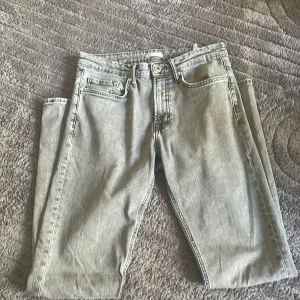 Grå jeans från Cubus - Snygga grå jeansbyxor från Cubus i rak modell. Klassisk femficksdesign med dragkedja och knapp i midjan. Jeansen har en tvättad look och passar perfekt till en avslappnad stil. Materialet är robust denim som håller länge. 