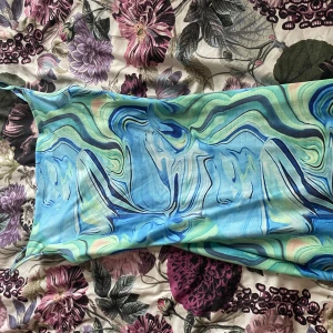 Blå mönstrad kortklänning  - Säljer en blå och grön swirlmönstrad kortklänning från SHEIN i storlek XS. Klänningen har tunna axelband och en figurnära passform. Materialet är mjukt och stretchigt.