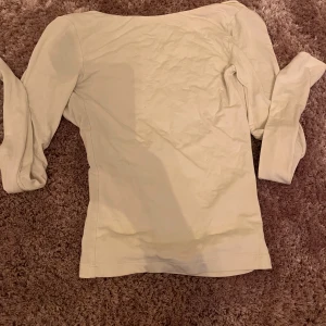 Beige långärmad topp Gina Tricot - Säljer en vit långärmad topp från Gina Tricot i storlek XXS. Toppen har en djup, rundad rygg och är figurnära i modellen. Materialet är mjukt och stretchigt, perfekt för att styla med jeans eller kjol. Enkel och clean design utan mönster eller detaljer.