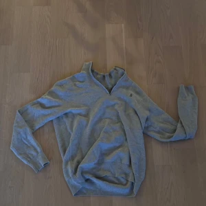 Grå half zip tröja från Polo Ralph Lauren - Helt ny Snygg grå långärmad tröja från Polo Ralph Lauren med half zip och klassisk broderad logga på bröstet. Tröjan är stickad i mjuk bomull och har en normal passform. Perfekt för dig som gillar stilrena och tidlösa plagg med premiumkänsla.