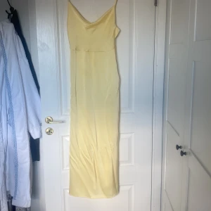Ljusgul långklänning från Vila - Supersnygg ljusgul långklänning från Vila i slinky polyester. Den är använd en gång då jag endast hade den på min avslutningsmiddag. Klänningen är öppen i ryggen. Köpte för 460. 